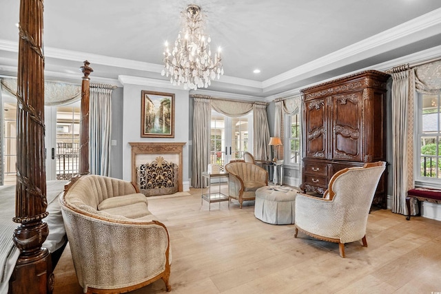 living area featuring a wealth of natural light, crown molding, light hardwood / wood-style flooring, and a notable chandelier