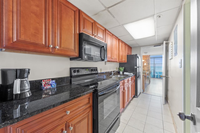 1501 S Ocean Blvd Unit 240, Myrtle Beach, SC 29577 - kitchen with black appliances, a paneled ceiling, light tile patterned flooring, dark stone counters, and brown cabinets
