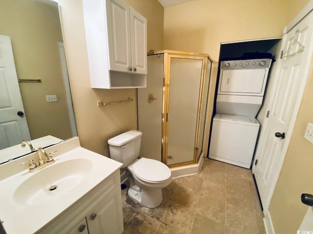 bathroom with a shower with door, vanity, stacked washer and clothes dryer, and toilet