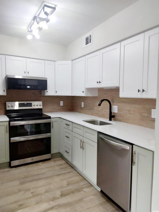 kitchen with white cabinets, appliances with stainless steel finishes, and light wood-type flooring