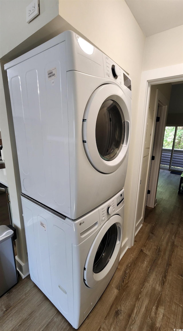 laundry area featuring stacked washer and clothes dryer and dark hardwood / wood-style flooring