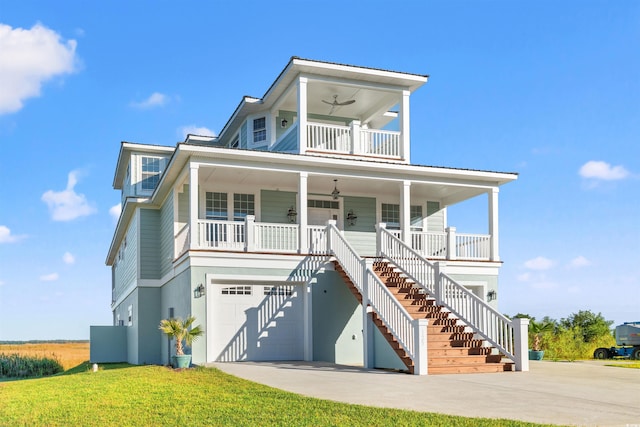 coastal inspired home with ceiling fan, covered porch, a front yard, and a garage