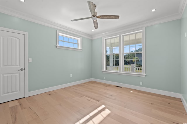 empty room with light hardwood / wood-style floors, crown molding, and a wealth of natural light