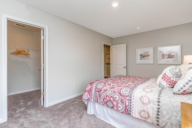 bedroom with a spacious closet, light colored carpet, and a closet