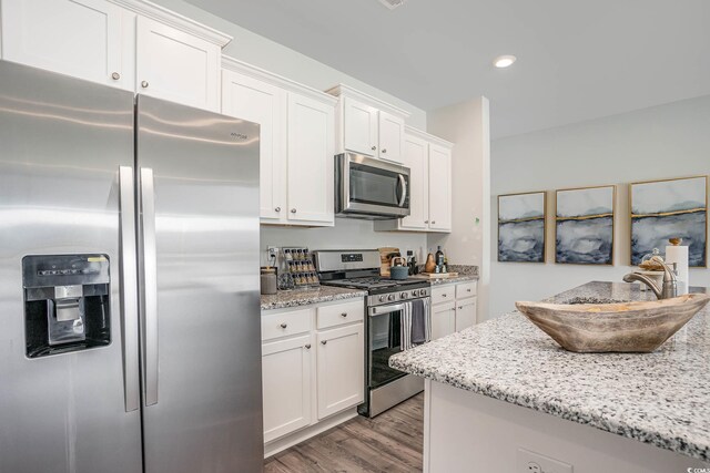 kitchen featuring light stone countertops, appliances with stainless steel finishes, white cabinets, and light hardwood / wood-style floors