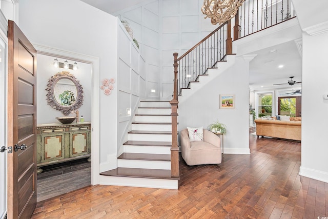 stairway with hardwood / wood-style flooring, a towering ceiling, and ceiling fan