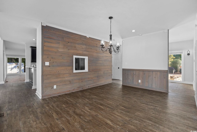 interior space featuring dark wood-type flooring, wood walls, ornamental molding, and plenty of natural light