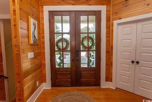 doorway to outside featuring plenty of natural light, french doors, light hardwood / wood-style floors, and wood walls