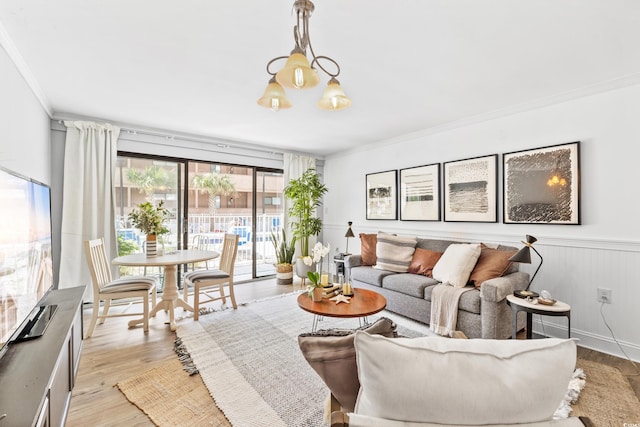 living room with a chandelier, crown molding, and light wood-type flooring