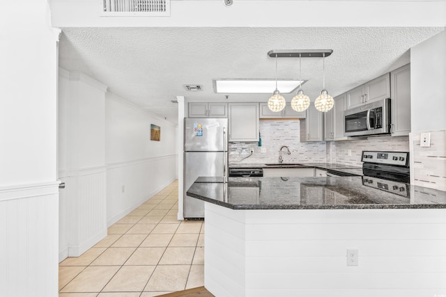 kitchen featuring backsplash, appliances with stainless steel finishes, sink, gray cabinetry, and decorative light fixtures