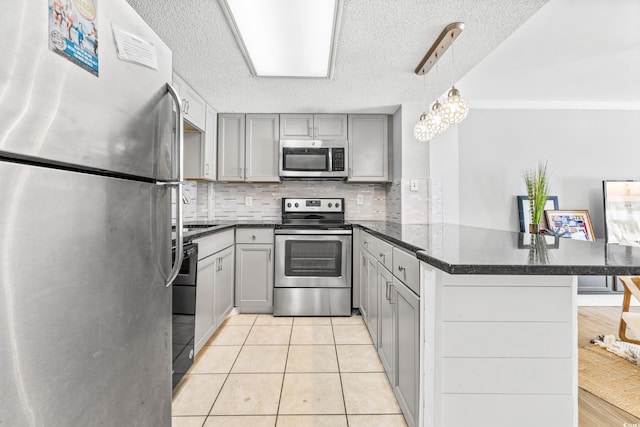 kitchen with gray cabinetry, a textured ceiling, kitchen peninsula, stainless steel appliances, and pendant lighting