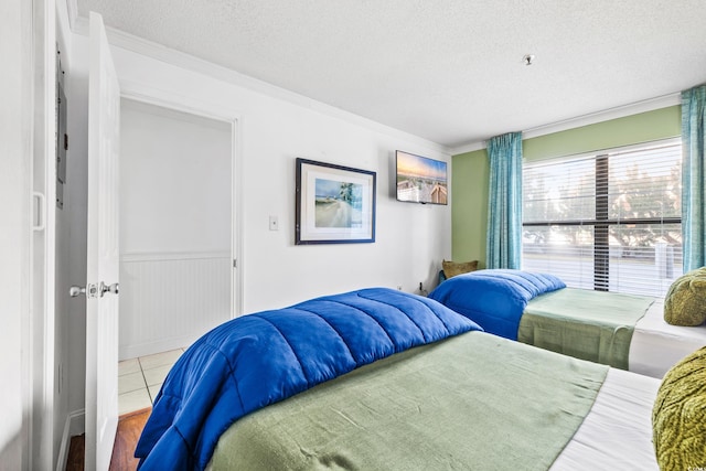 bedroom with crown molding, a textured ceiling, and light hardwood / wood-style flooring