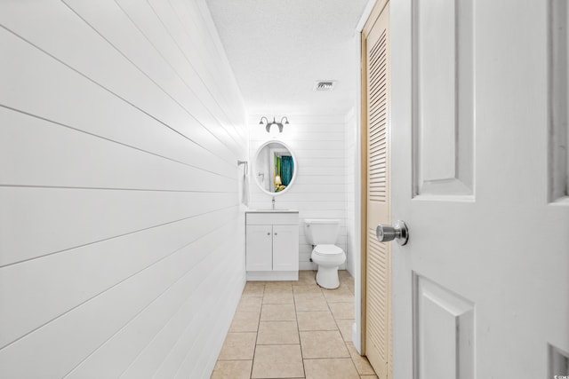 bathroom featuring vanity, toilet, a textured ceiling, and tile patterned flooring