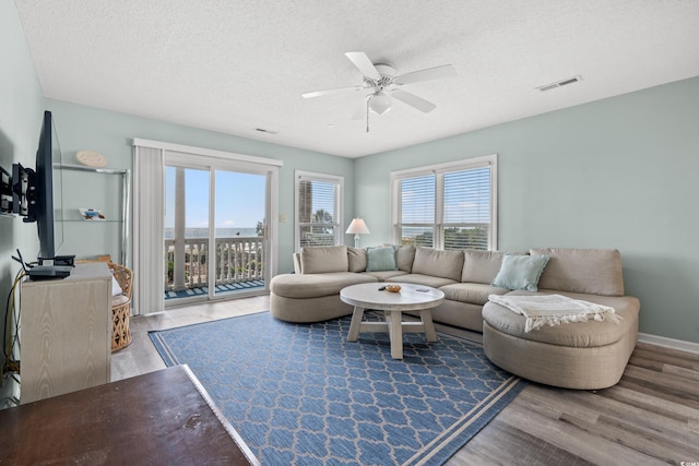 living room with wood-type flooring, ceiling fan, and a textured ceiling