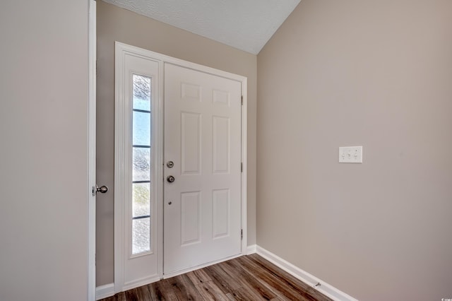 foyer featuring a textured ceiling, vaulted ceiling, and dark wood-type flooring