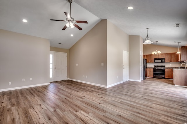 unfurnished living room with ceiling fan with notable chandelier, light hardwood / wood-style floors, and high vaulted ceiling