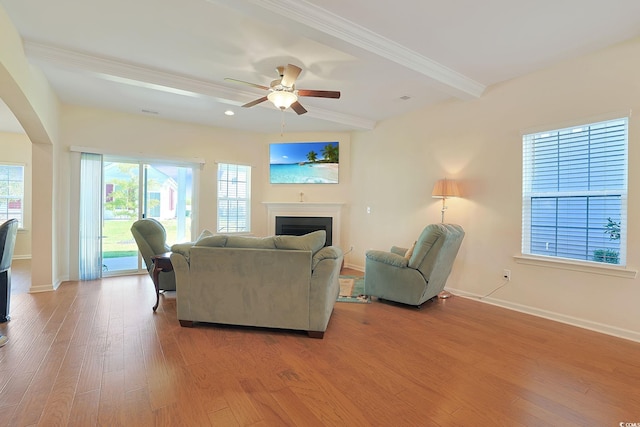 living room featuring beamed ceiling, light wood-type flooring, and ceiling fan