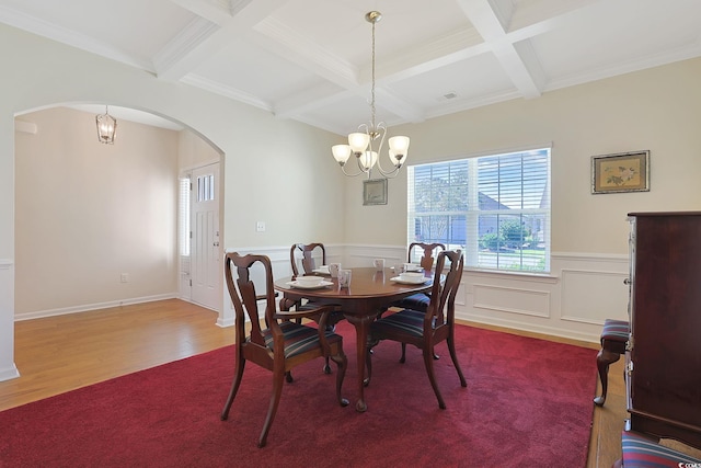 dining area with beamed ceiling, hardwood / wood-style floors, crown molding, coffered ceiling, and an inviting chandelier