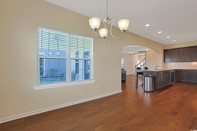 kitchen featuring hanging light fixtures, an island with sink, dark hardwood / wood-style floors, and a wealth of natural light