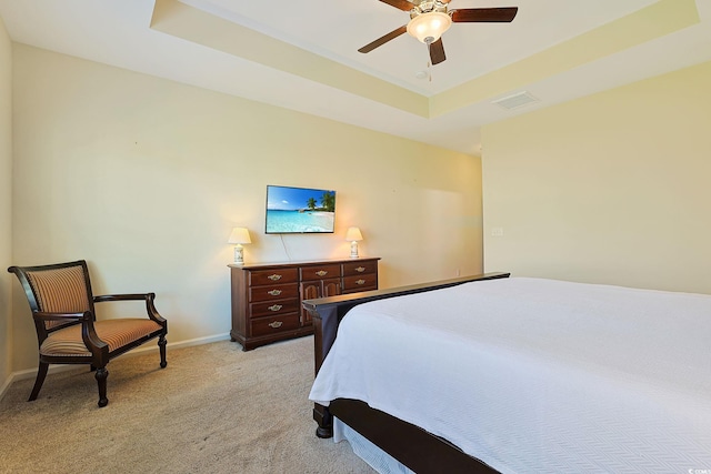 carpeted bedroom featuring ceiling fan and a raised ceiling