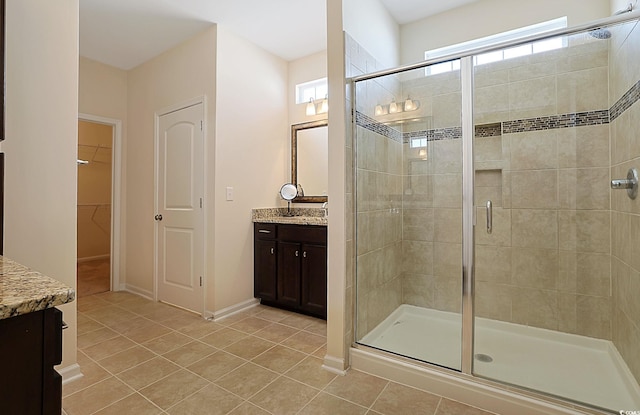 bathroom featuring tile patterned floors, a healthy amount of sunlight, vanity, and a shower with shower door