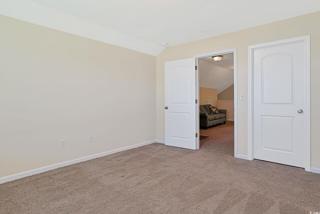 spare room featuring light carpet and vaulted ceiling