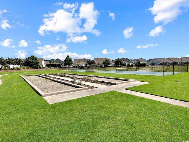 view of home's community with tennis court and a yard