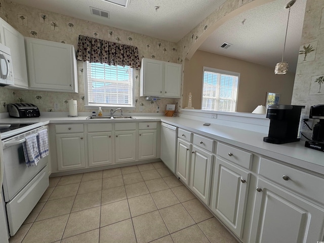 kitchen with sink, hanging light fixtures, a textured ceiling, white appliances, and white cabinets