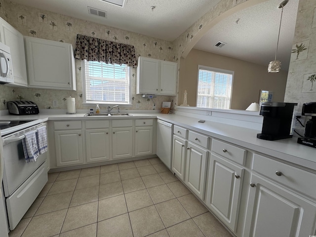 5801 Oyster Catcher Dr Unit 1531, North Myrtle Beach, SC 29582 - kitchen with white appliances, a sink, light tile patterned floors, white cabinets, and arched walkways