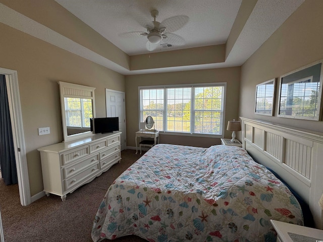 bedroom with dark colored carpet, a textured ceiling, and ceiling fan