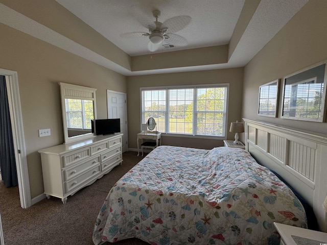 5801 Oyster Catcher Dr Unit 1531, North Myrtle Beach, SC 29582 - bedroom with dark carpet, baseboards, a ceiling fan, a tray ceiling, and a textured ceiling