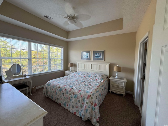 bedroom featuring ceiling fan, dark carpet, and a textured ceiling