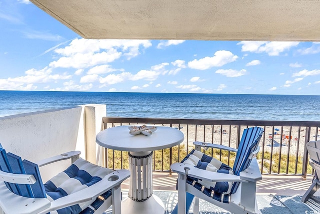 balcony with a water view and a view of the beach