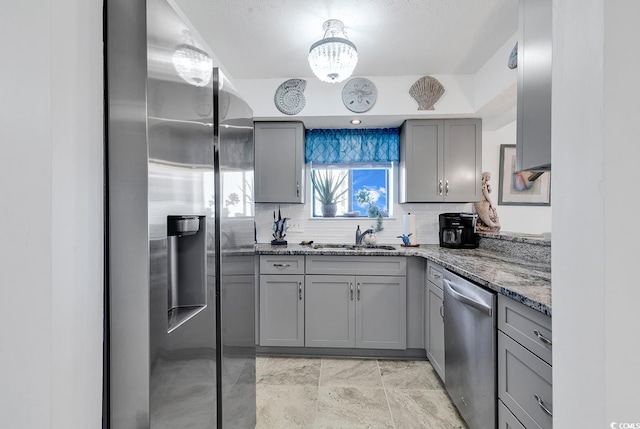 kitchen featuring sink, tasteful backsplash, gray cabinetry, stainless steel appliances, and dark stone counters