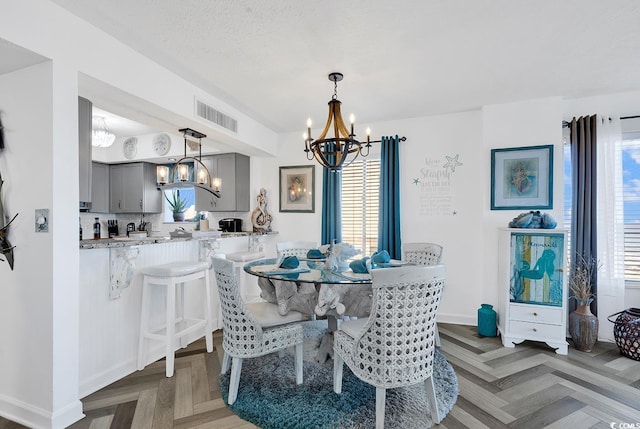 dining area with parquet flooring, a chandelier, and a textured ceiling