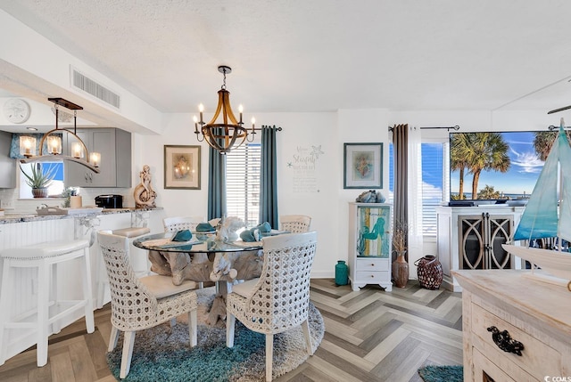 dining area with a healthy amount of sunlight, light parquet floors, an inviting chandelier, and a textured ceiling