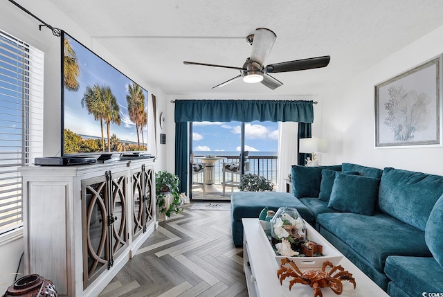 living room featuring ceiling fan, parquet floors, and a textured ceiling