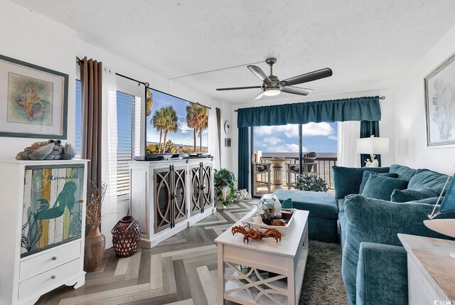 living room with ceiling fan, dark parquet floors, and a textured ceiling