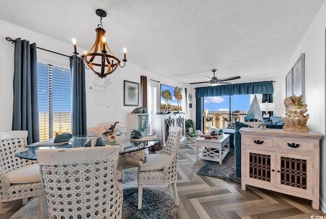 dining space featuring ceiling fan with notable chandelier, parquet floors, and a textured ceiling