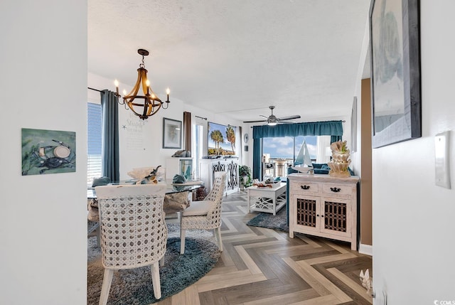 dining area with ceiling fan with notable chandelier, dark parquet flooring, and a textured ceiling