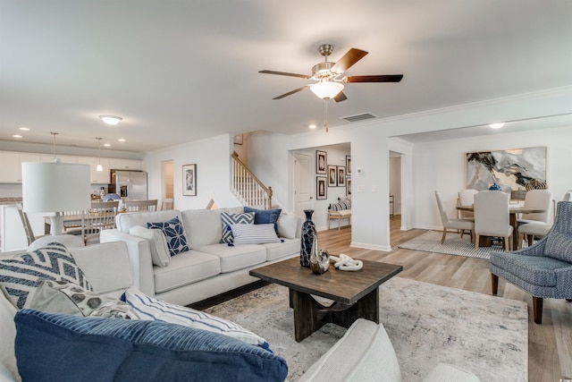 living room with ceiling fan, ornamental molding, and light hardwood / wood-style flooring