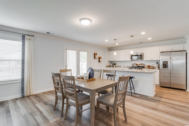 dining room featuring light wood-type flooring and crown molding