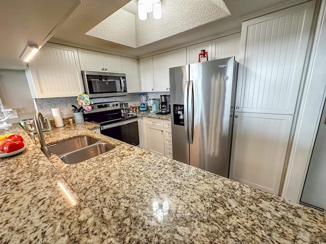 kitchen with appliances with stainless steel finishes, decorative backsplash, white cabinets, and sink