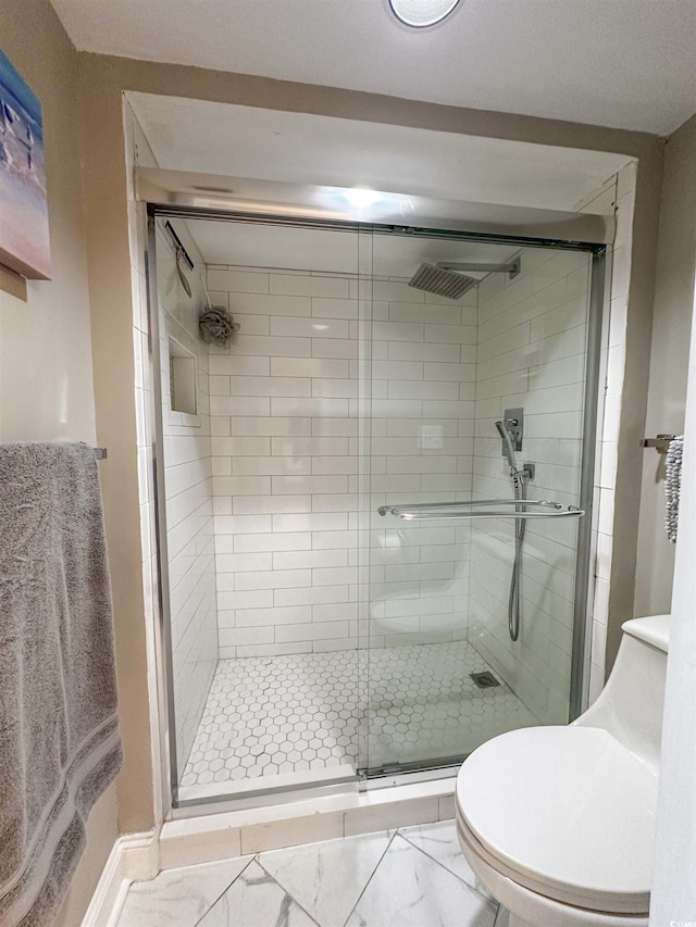 bathroom featuring toilet and a shower with shower door