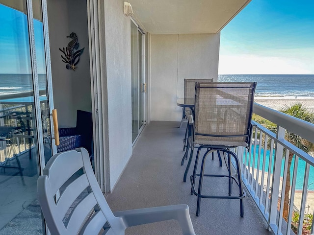 balcony featuring a water view and a beach view