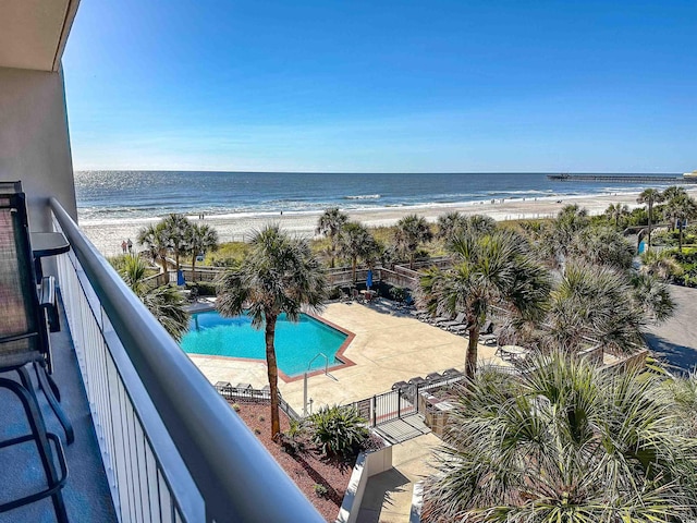 view of pool featuring a water view, a patio area, and a beach view