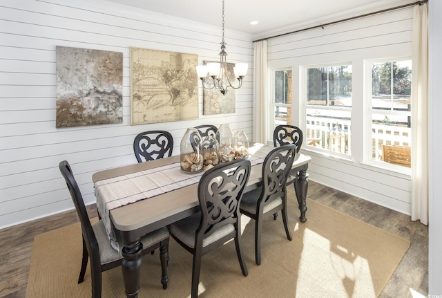 dining room featuring wooden walls, a notable chandelier, and dark hardwood / wood-style floors