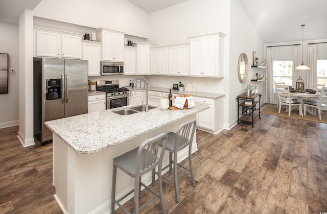 kitchen with an island with sink, pendant lighting, white cabinetry, appliances with stainless steel finishes, and dark hardwood / wood-style flooring