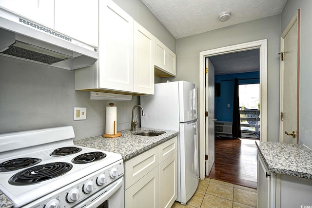 kitchen featuring light hardwood / wood-style floors, white appliances, light stone counters, white cabinets, and a textured ceiling