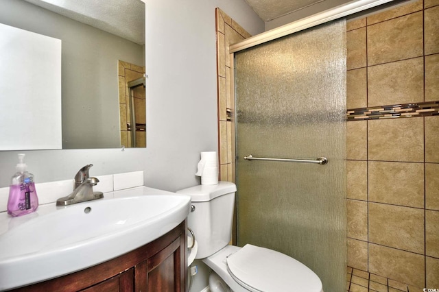 bathroom featuring vanity, a shower with door, toilet, and a textured ceiling